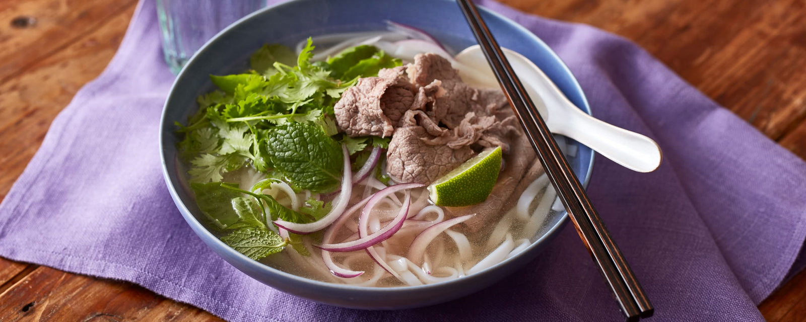 Beef pho with rice noodles, fresh herbs, red onion, and lime