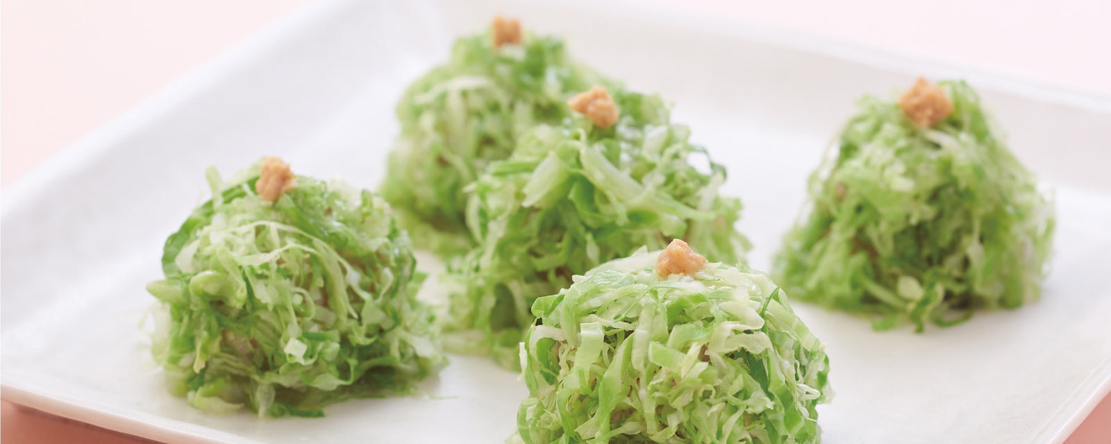 Vibrant green cabbage-wrapped shumai dumplings with Japanese mustard.
