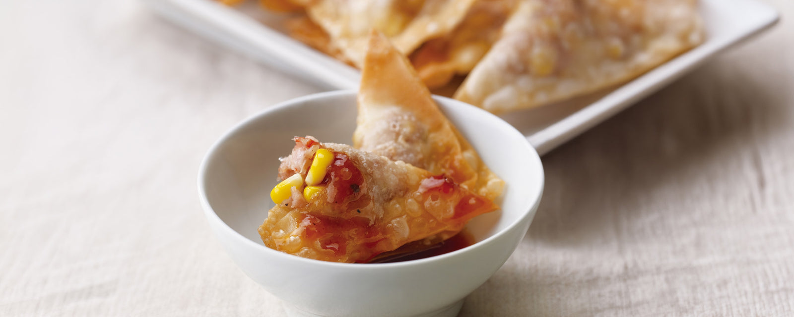 Crispy fried wontons served with homemade chili sauce on a plate