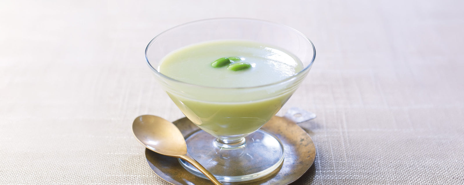 Chilled edamame soup garnished with whole edamame beans in a glass bowl