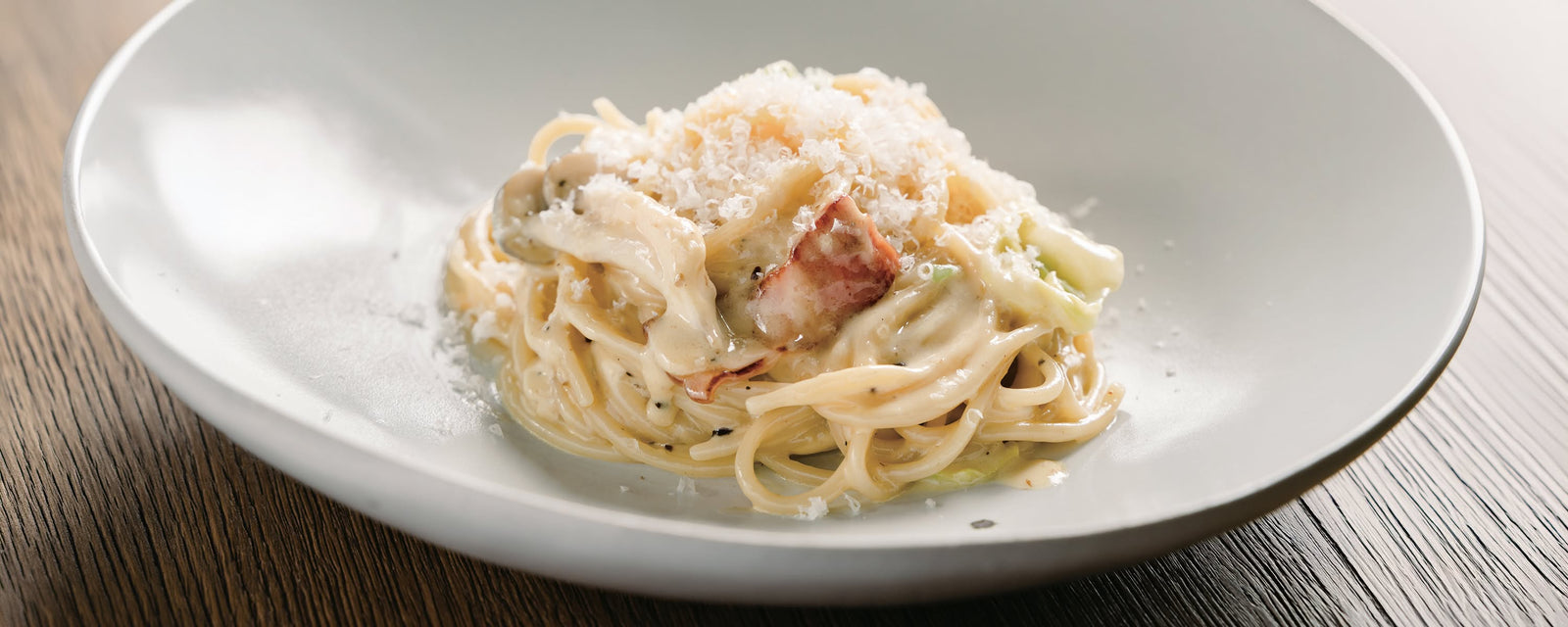 Creamy Corn Dashi Pasta with bacon, mushrooms, cabbage, and Parmesan cheese, topped with freshly grated cheese.