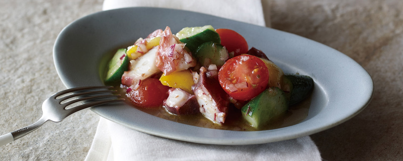 A colorful marinated octopus salad with fresh vegetables in a light lemon and dashi dressing.