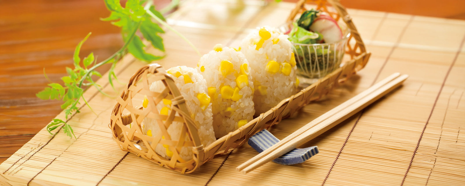Japanese corn rice balls made with Kayanoya Original Dashi Stock Powder, featuring sweet corn and served in a woven bamboo basket.