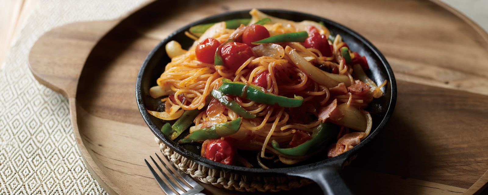 A skillet of Napolitan (Japanese Ketchup Pasta) with bacon, onions, green peppers, mushrooms, cherry tomatoes, and Kayanoya Original Dashi.