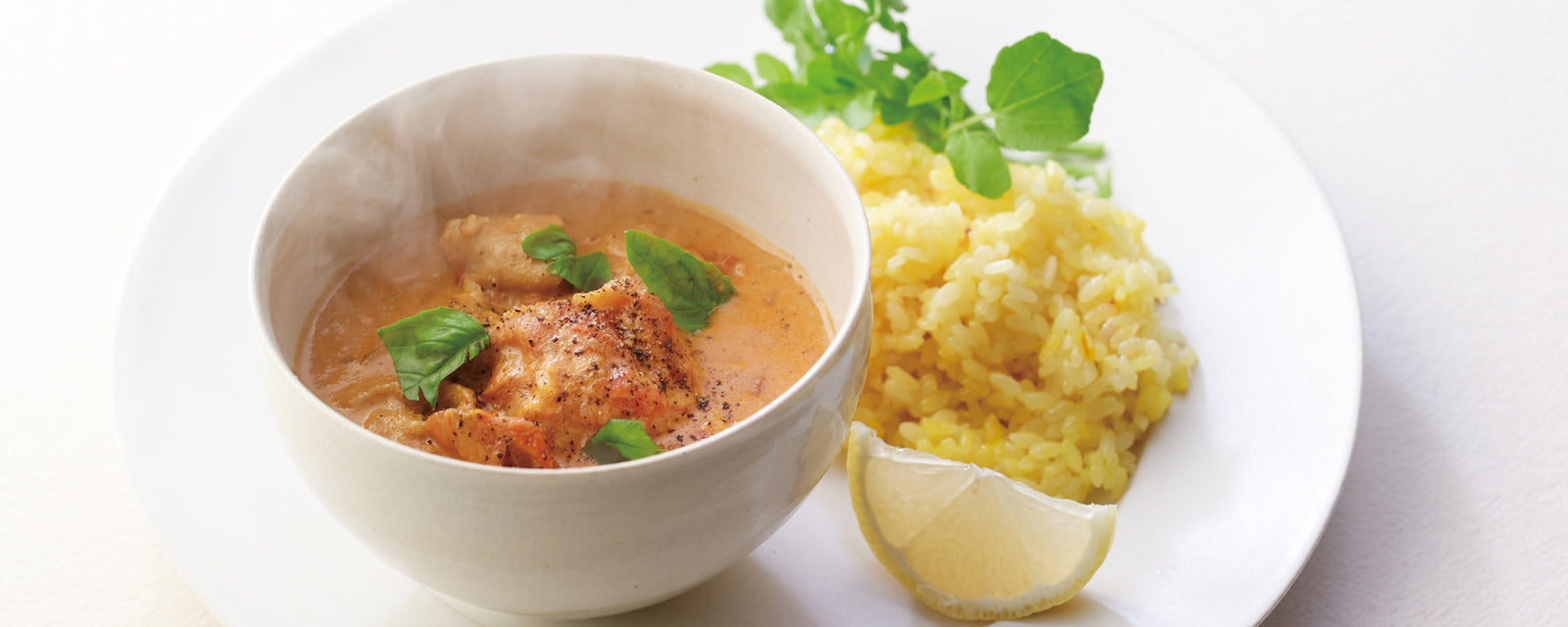 Creamy chicken tomato curry served with turmeric rice, lemon wedge, and fresh herbs