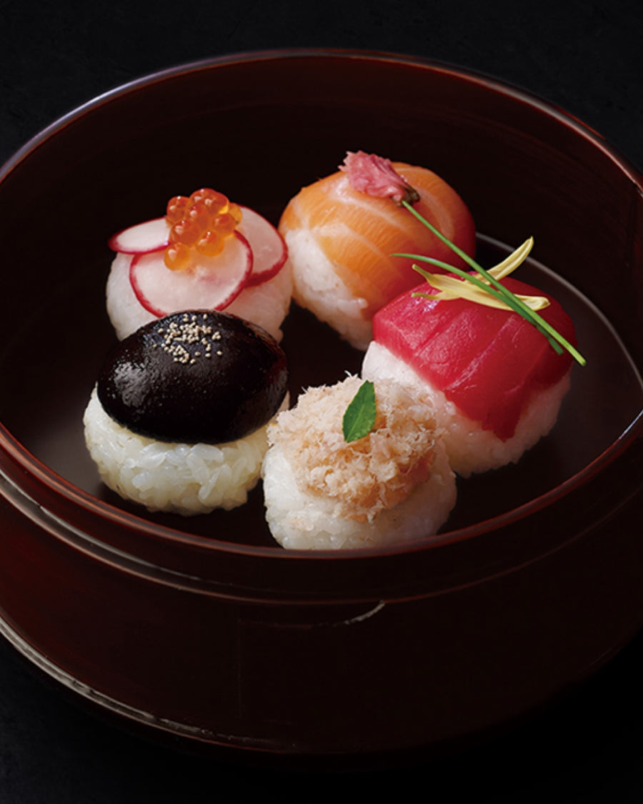 Assorted decorative temari sushi with salmon, tuna, ikura, shiitake, and radish toppings in a lacquer bowl