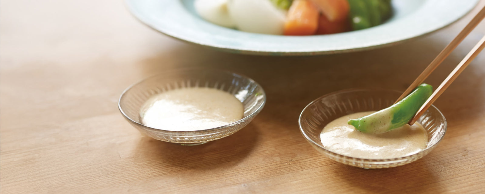 Fresh vegetables dipped in a creamy sauce, served in small glass bowls with chopsticks