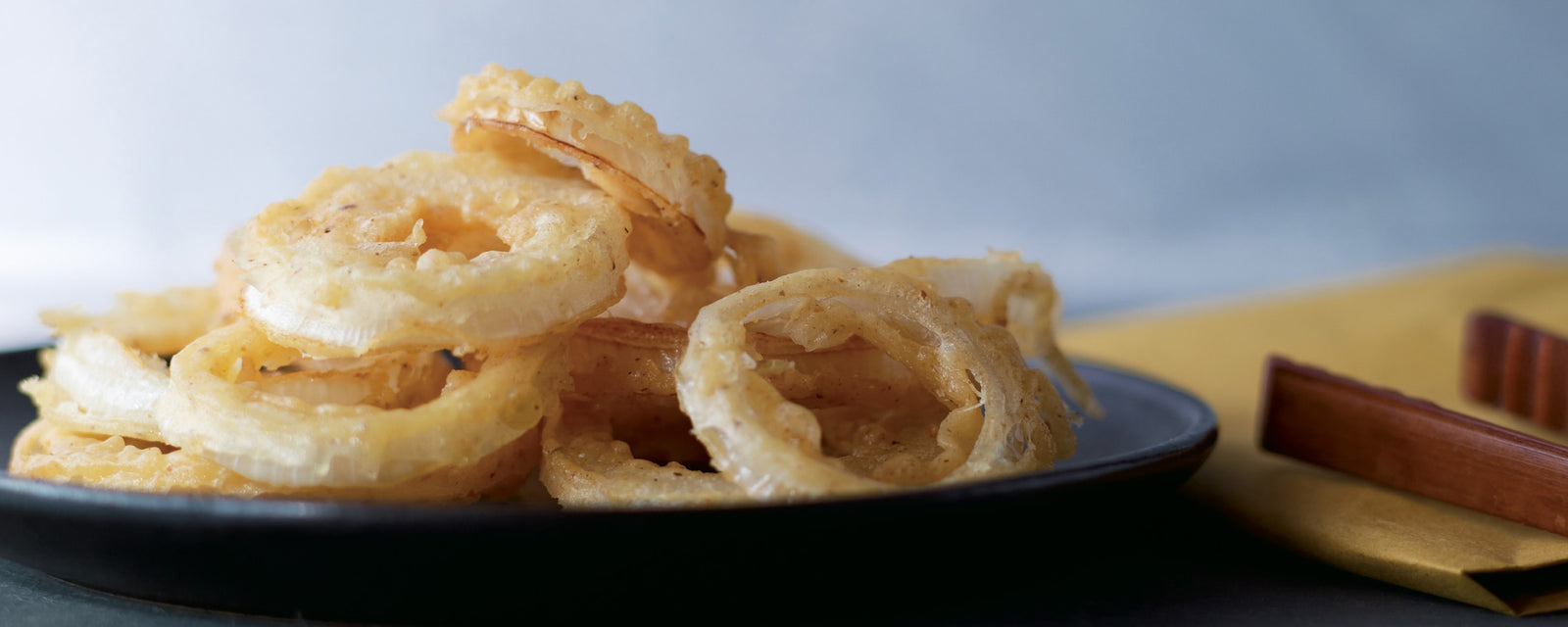 Crispy fried onion rings stacked on a plate, golden and lightly battered