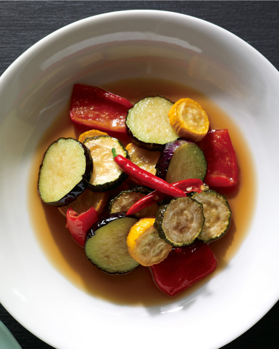 Marinated zucchini and bell peppers in a light broth, topped with red chili peppers and served in a white bowl