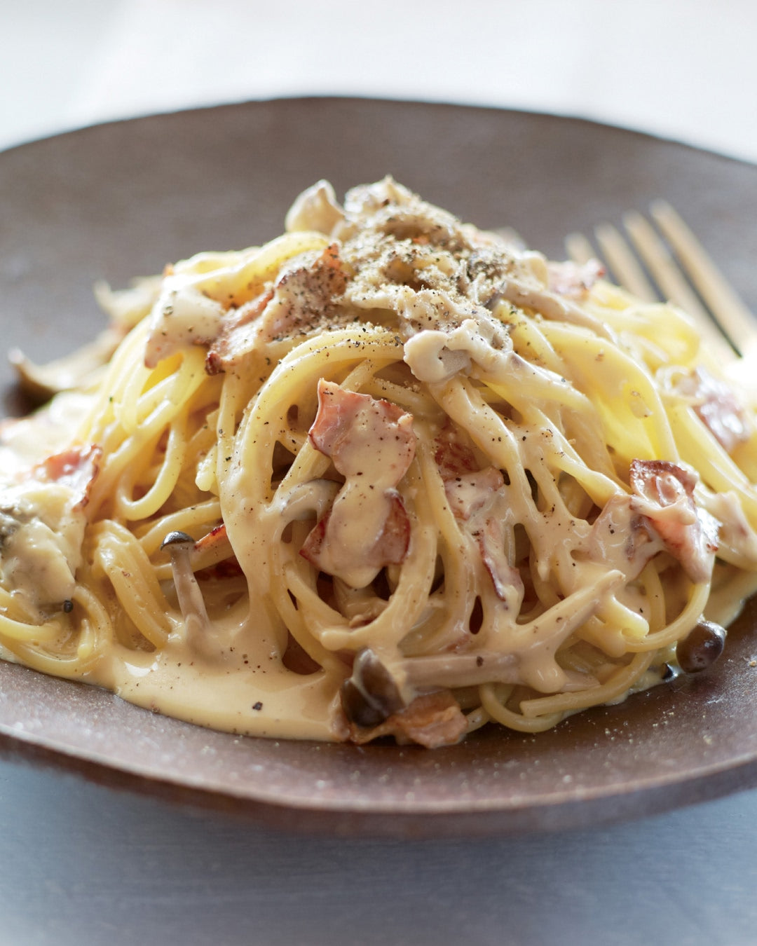 Creamy pasta with bacon and mushrooms in a rich dashi-infused sauce, finished with black pepper