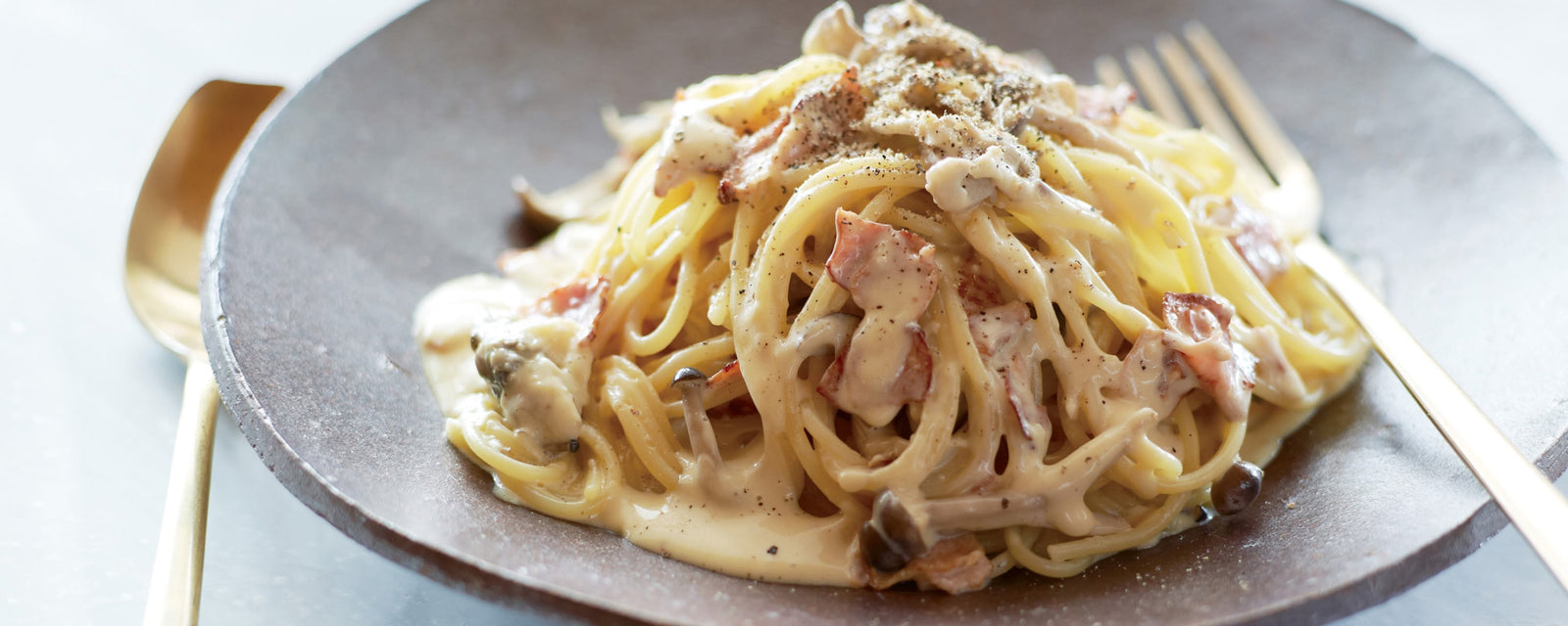 Creamy pasta with bacon and mushrooms in a rich dashi-infused sauce, finished with black pepper