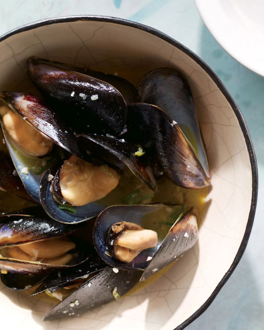 Steamed mussels in a light dashi broth with garlic and herbs, served in a rustic bowl
