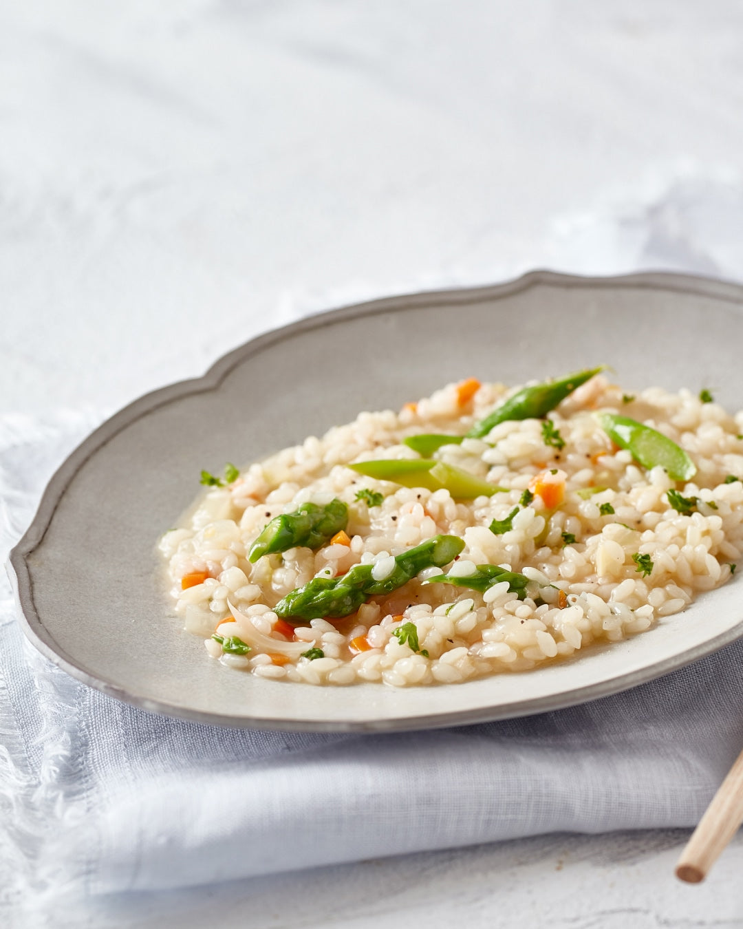 Dashi risotto with tender rice, asparagus, and finely chopped vegetables in a light savory broth