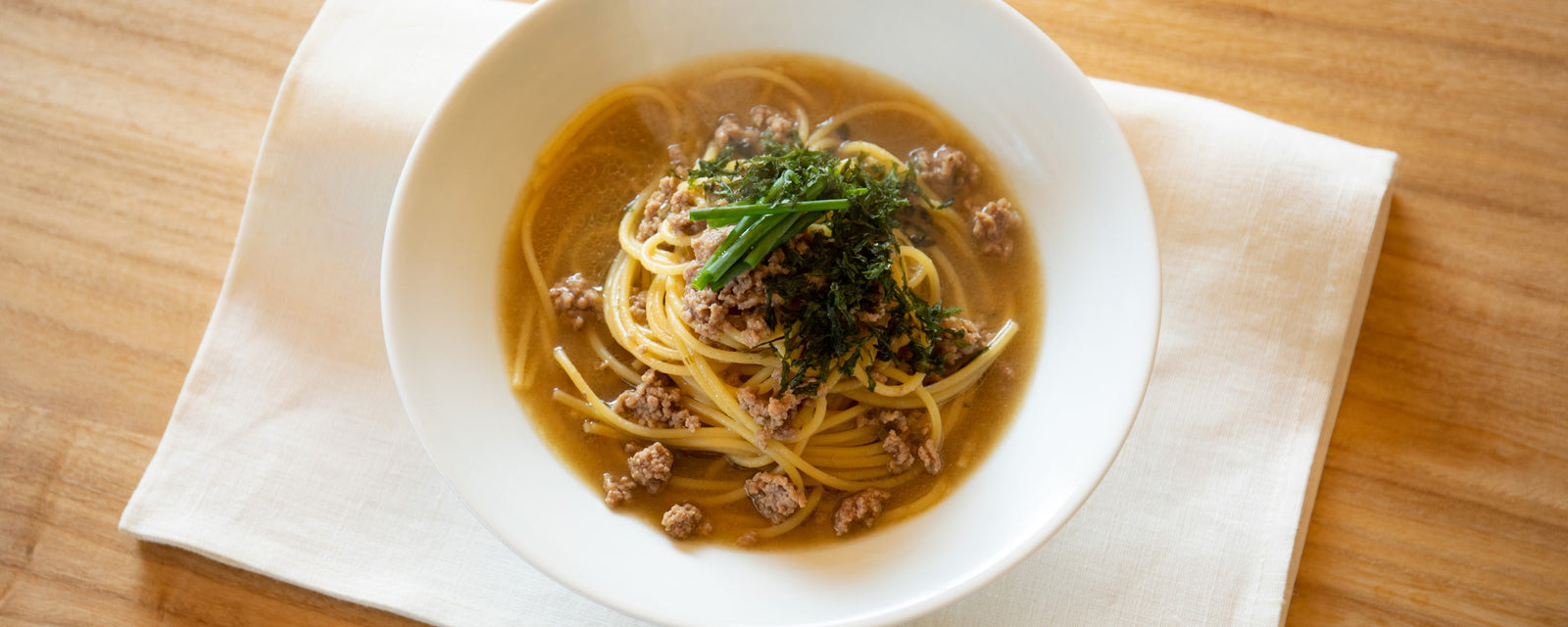 Spaghetti in savory umami dashi broth topped with green onions