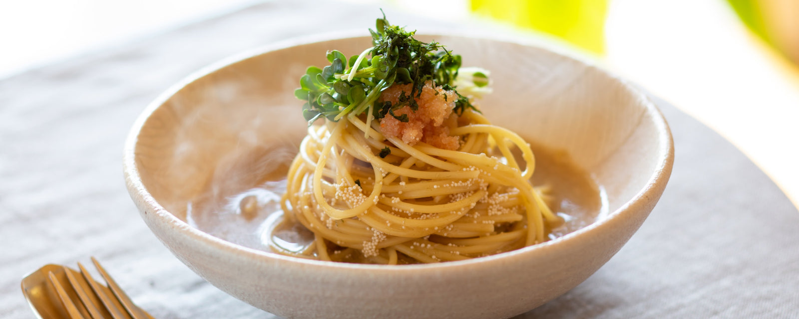 Spaghetti topped with spicy cod roe and daikon radish sprouts in light soy-based broth