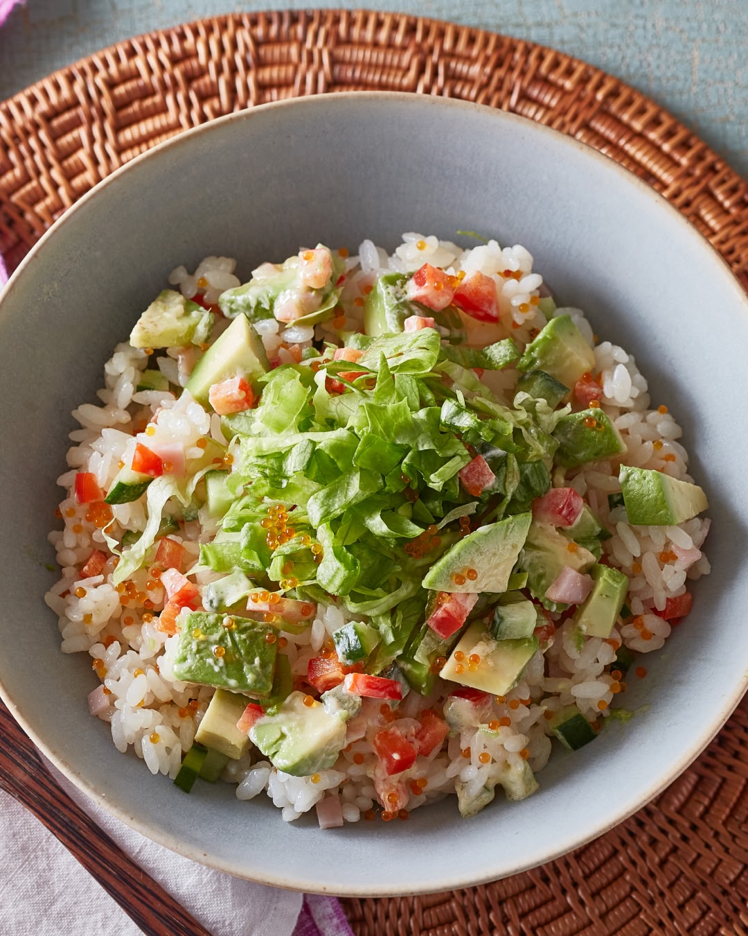 Avocado and vegetable mixed rice bowl topped with lettuce and tobiko