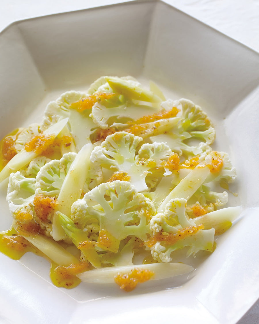Cauliflower and white asparagus salad with carrot dressing on a white plate