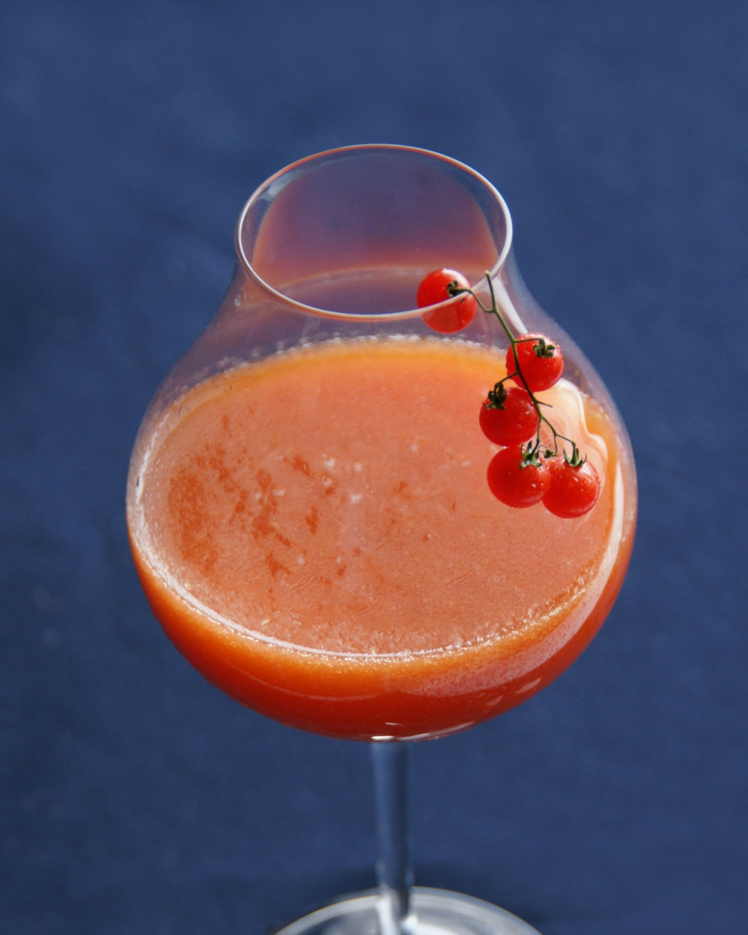 Chilled tomato soup garnished with cherry tomatoes in a stemmed glass
