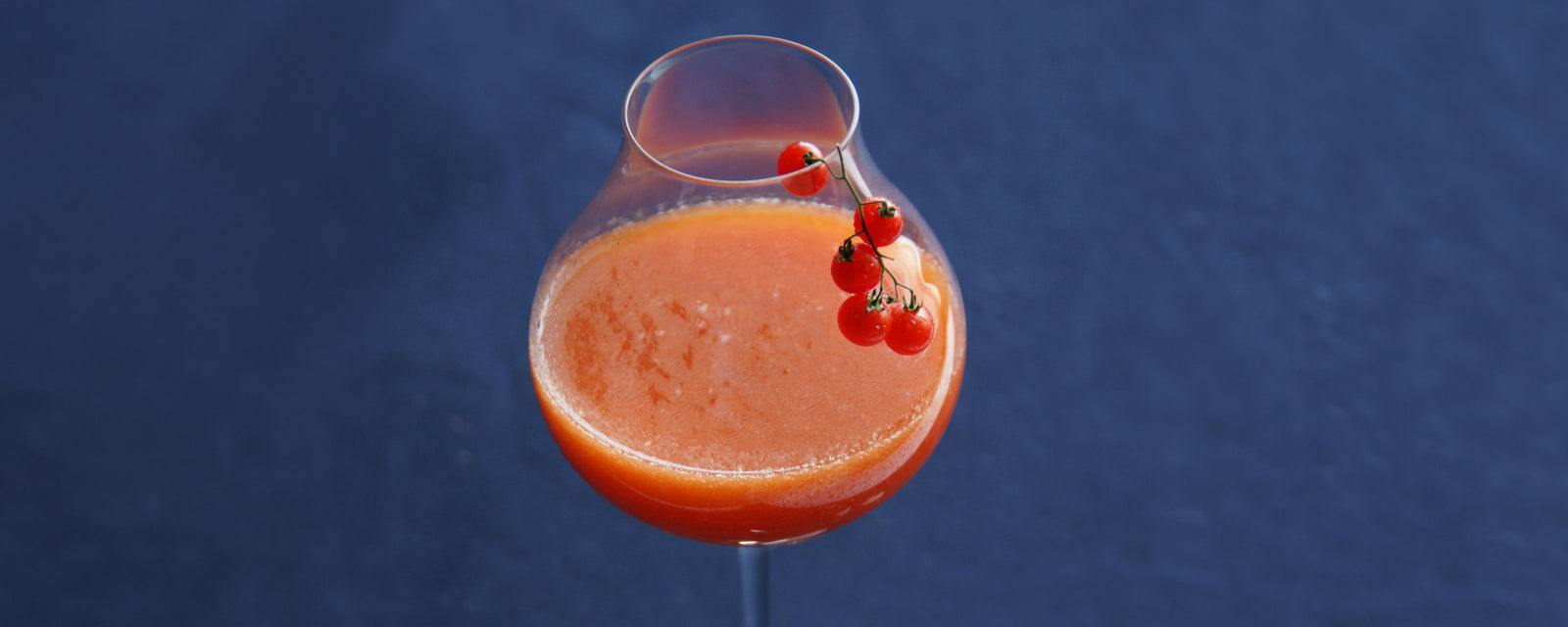 Chilled tomato soup garnished with cherry tomatoes in a stemmed glass