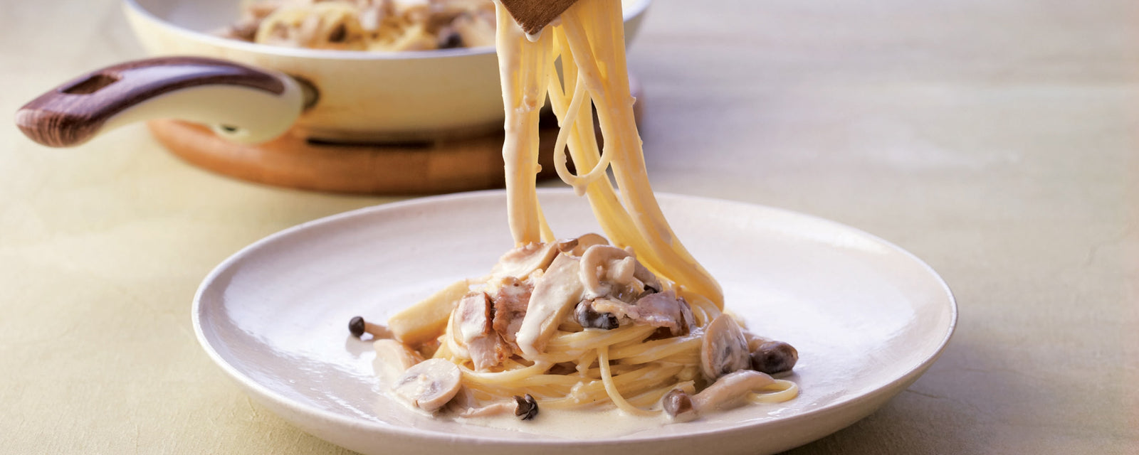 Creamy mushroom pasta with bacon being lifted from a plate