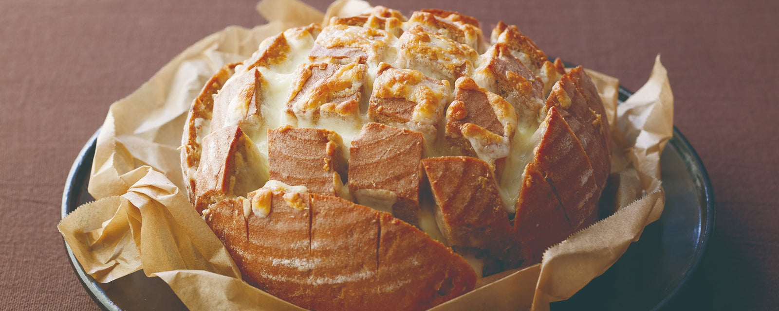 Cheese-filled pull-apart bread baked until golden and served in parchment-lined dish