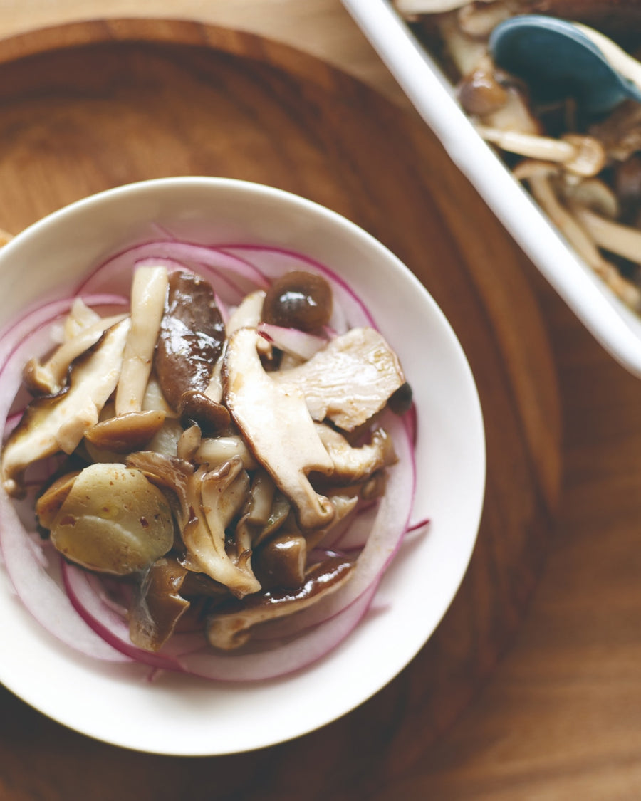 Marinated mushrooms and red onion salad served in a small bowl with bread