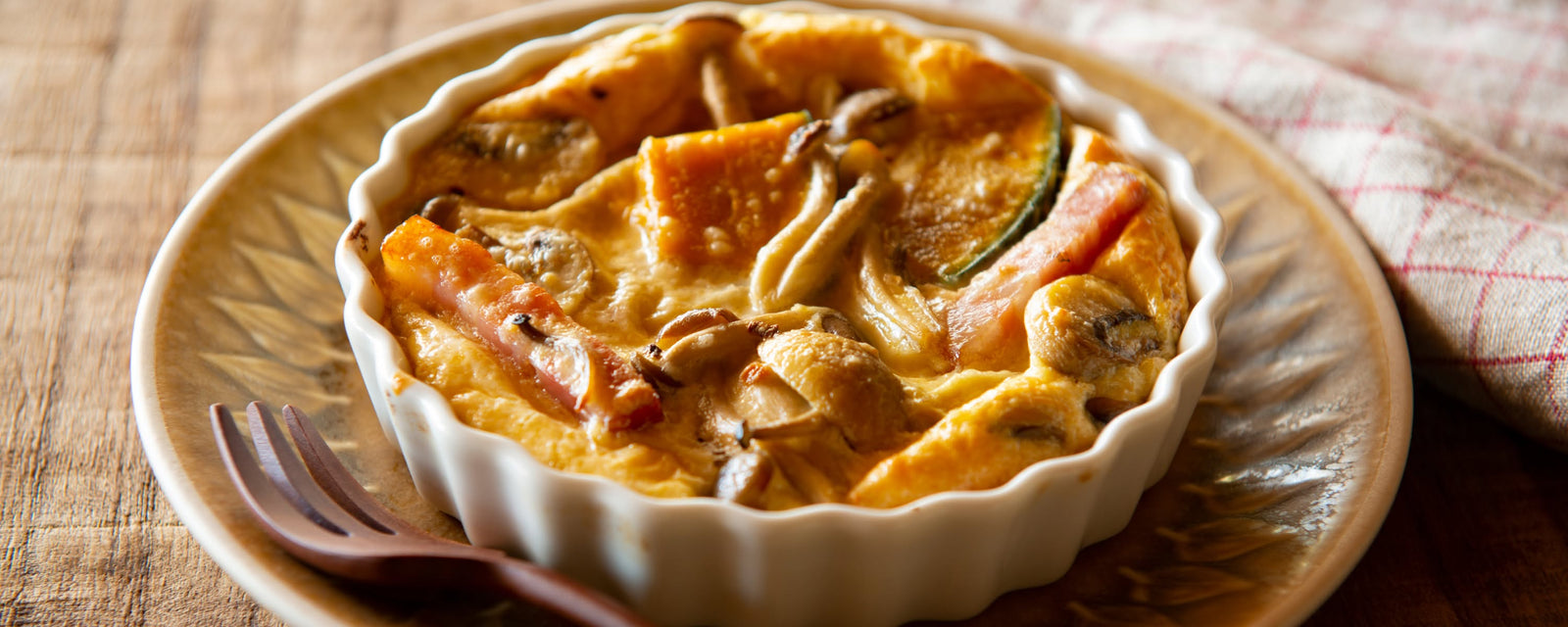 Baked pumpkin and mushroom gratin with bacon in a small ceramic dish