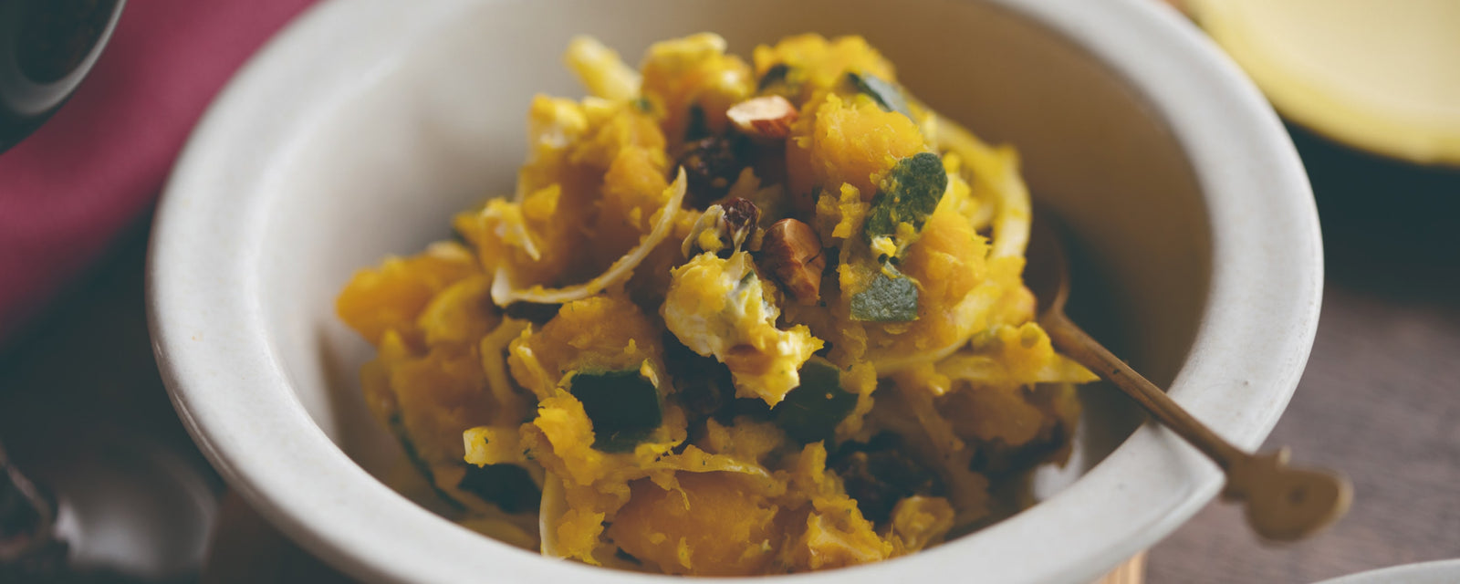 Mashed pumpkin salad with nuts, onions, and raisins in a small bowl.