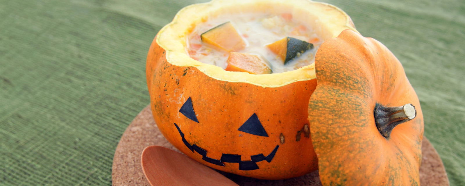 Pumpkin soup served in a carved pumpkin with a jack-o’-lantern face.