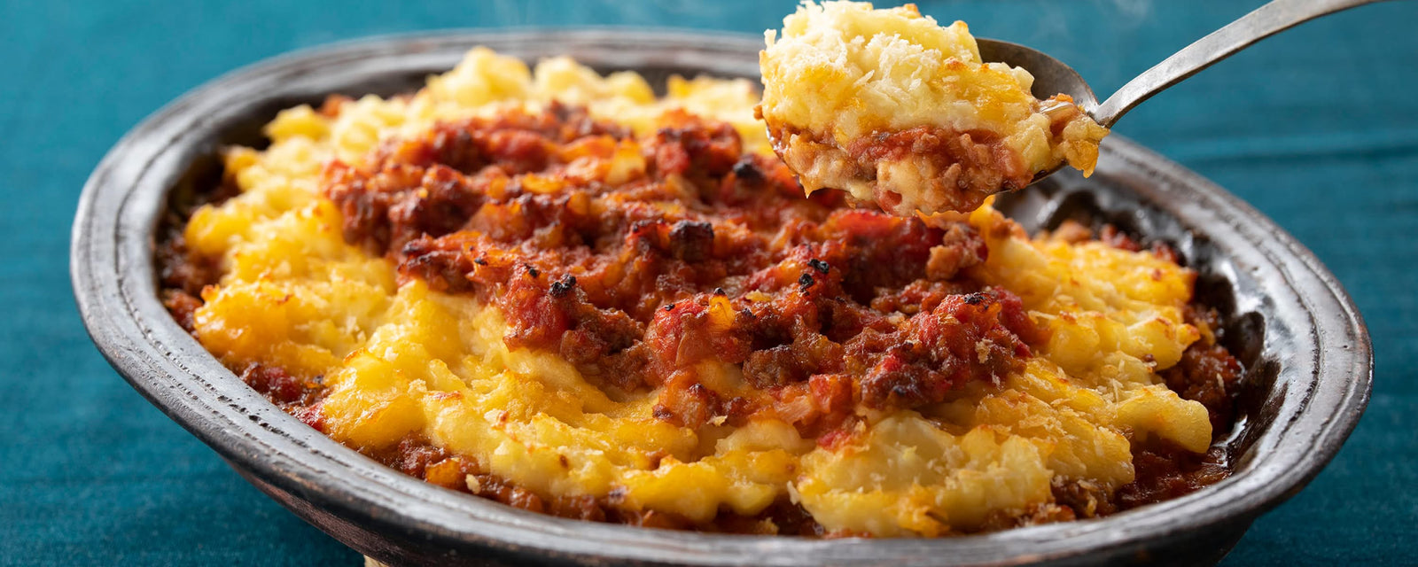 Baked mashed potato casserole with meat sauce, served in a dish.