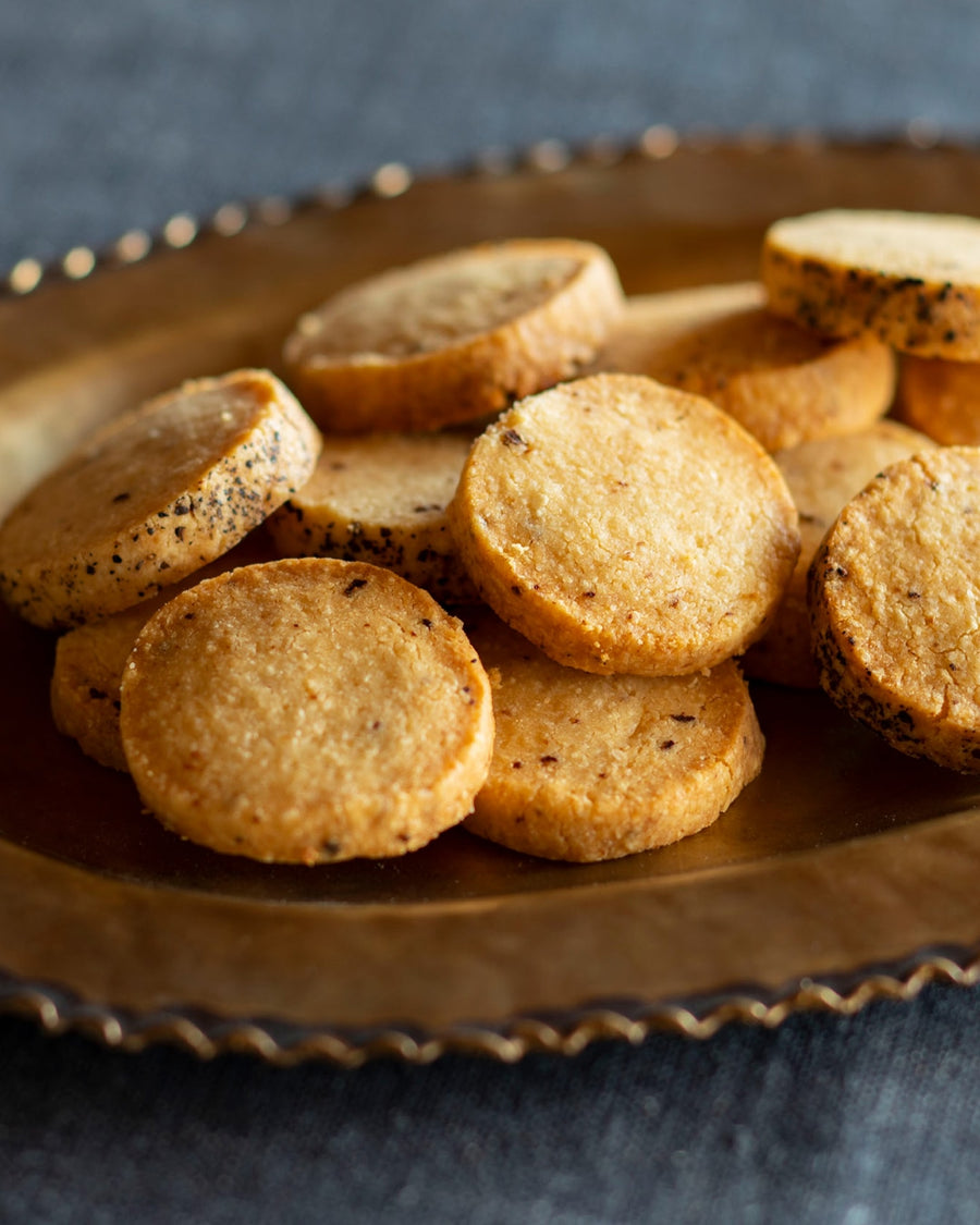Round savory cookies with black pepper served on a metal plate.