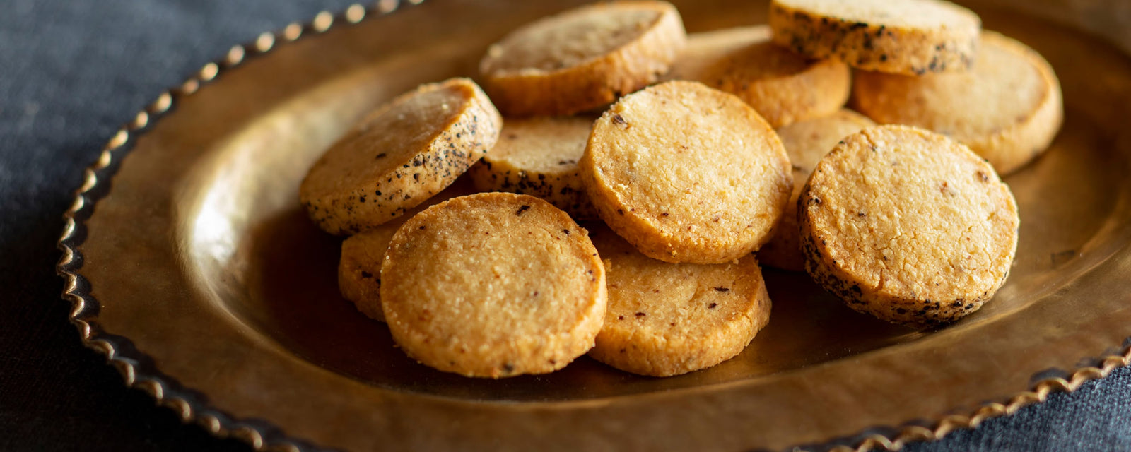Round savory cookies with black pepper served on a metal plate.