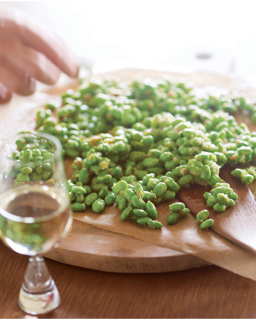 Crispy green beans on parchment paper with a glass of white wine.