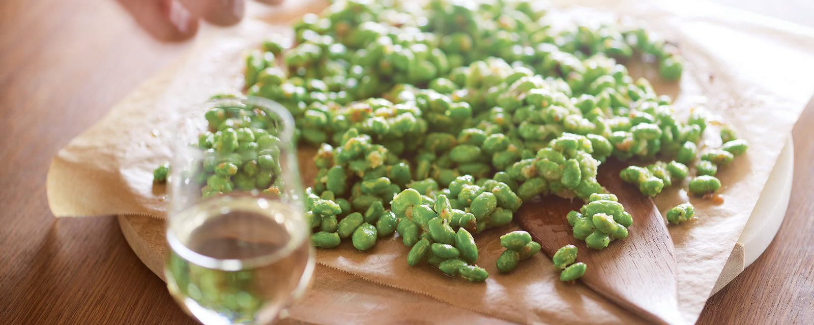 Crispy green beans on parchment paper with a glass of white wine.
