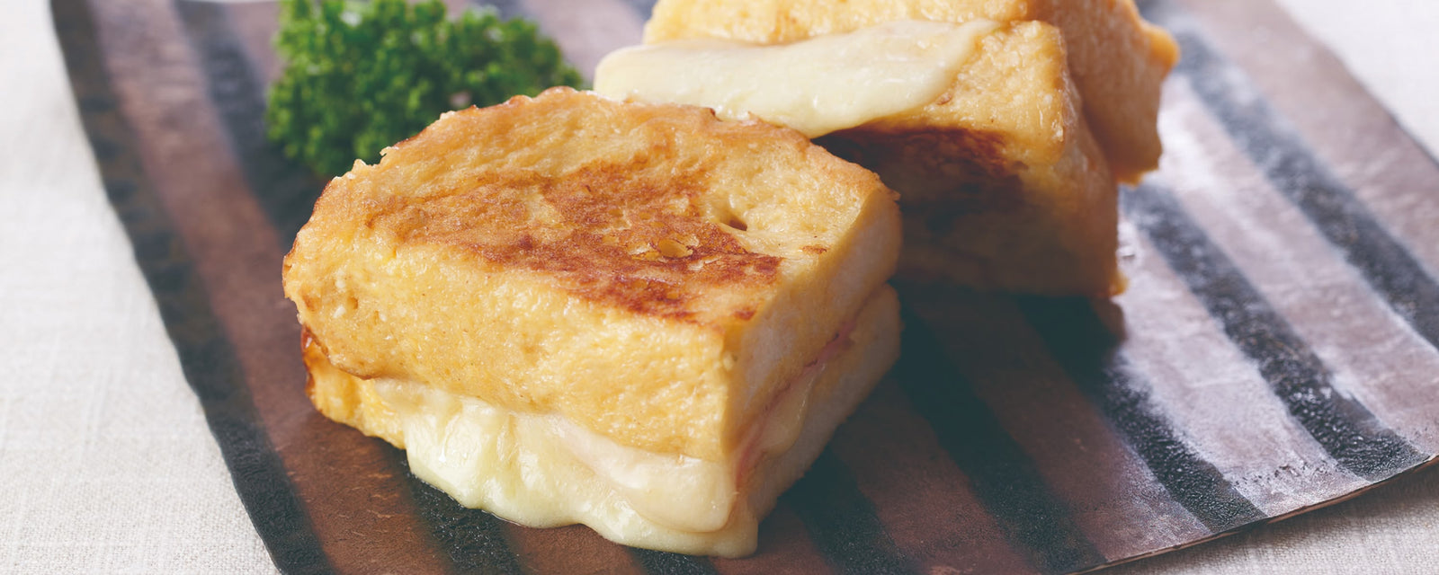 Thick French toast stuffed with melted cheese on a plate.