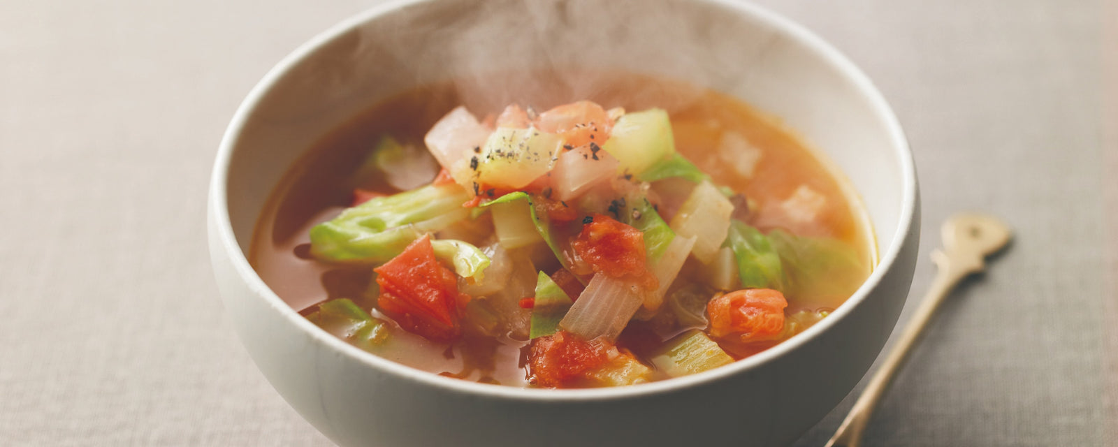 Hot vegetable soup with tomatoes, celery, and cabbage in a bowl.