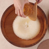 Mixing sushi rice with vinegar in a wooden tub using a rice paddle