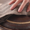Taking off the lid of a clay pot to reveal freshly cooked rice and a kombu dashi packet on top of it.
